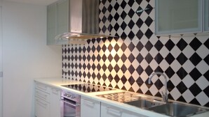 Een keuken met witte kasten, een roestvrijstalen spoelbak en een zwart-wit betegelde achterwand in een diamantpatroon.
