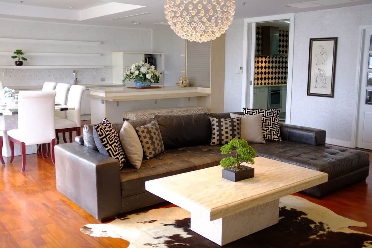A modern living room with a sectional sofa, a coffee table, and a dining area with a white table and chairs.