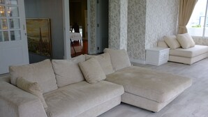 Een moderne woonkamer met een grote beige modulaire bank, een kleinere bank en een witte nachtkastje.