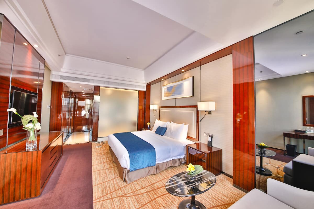 Una habitación de hotel con una cama grande, un escritorio, una silla, una mesita y un espejo.