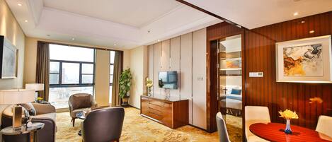 Una habitación de hotel con sala de estar, una mesa de comedor y un televisor en la pared.
