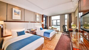 Une chambre d’hôtel avec deux lits, un bureau, une télévision et une grande fenêtre.