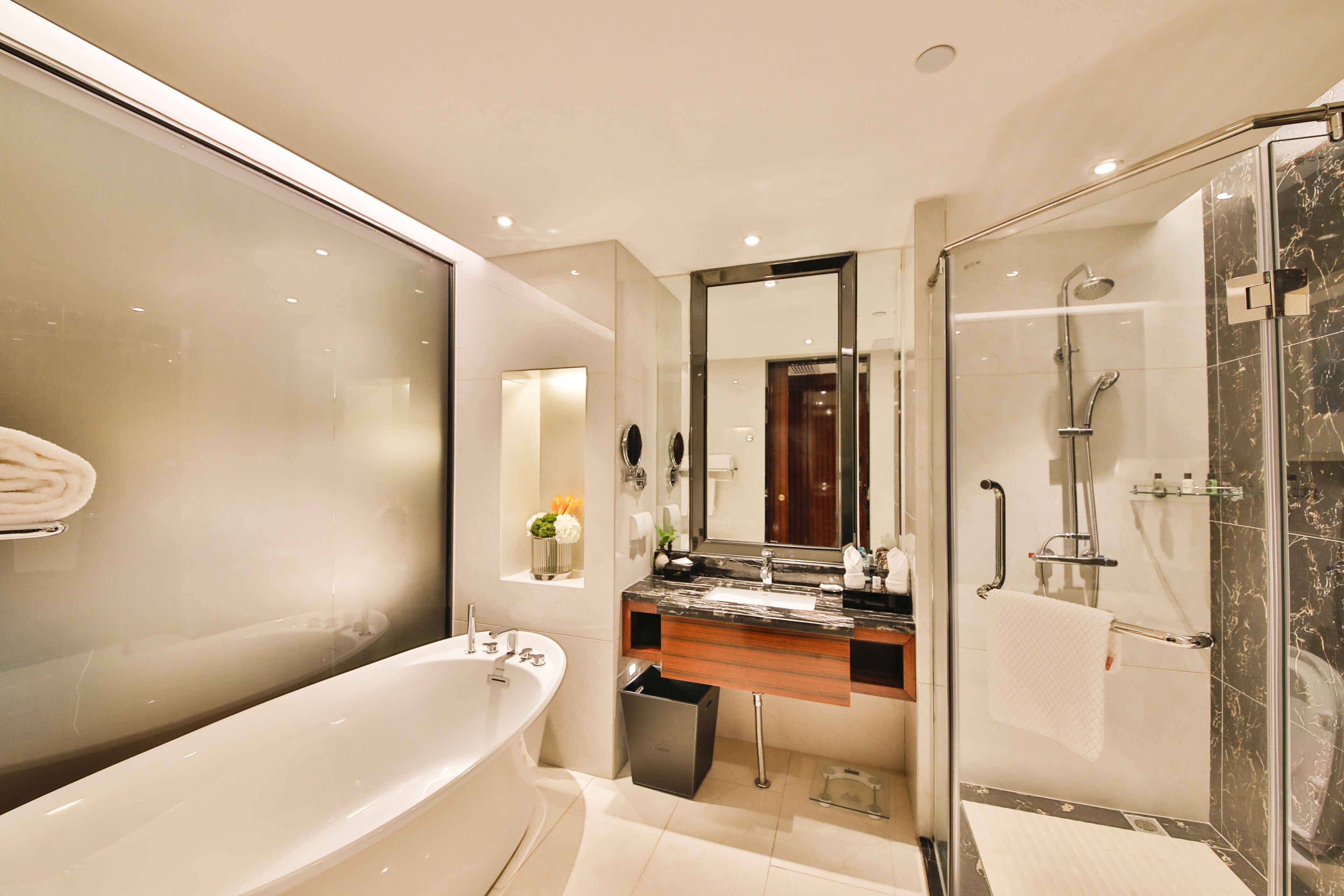 A modern bathroom with a freestanding bathtub, a glass-enclosed shower, and a vanity with a marble countertop.