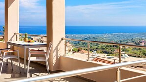 A balcony with a table and chairs, overlooking a scenic view of the sea and a hilly landscape. - Villa di Giorgio Heated Pool (Apokoronas)