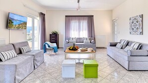 A modern living room with two grey sofas, a coffee table with fruit, and a large window with curtains. - Villa di Giorgio Heated Pool (Apokoronas)