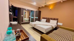A hotel room with a bed, a desk with a chair, a wardrobe, and a mirror. - Hotel Ashapura Palace by Sky Stays (Nathdwara)