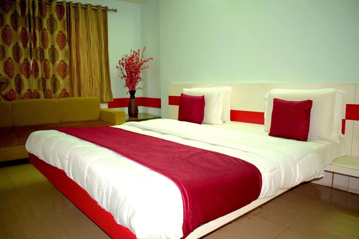 A hotel room with a large bed, a sofa, and a vase with flowers.