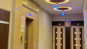 A hotel corridor with a modern ceiling design featuring circular light fixtures and a central column. - Hotel Ashapura Palace by Sky Stays (Nathdwara)