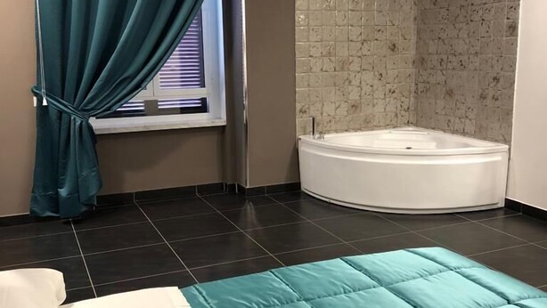 Ein modernes Badezimmer mit einer Badewanne, einem Fenster mit Vorhängen und einer gefliesten Duschwand.
