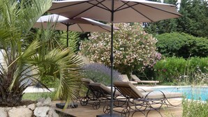 A poolside area with lounge chairs and a large umbrella.