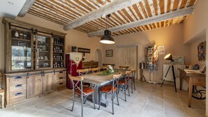 A rustic kitchen with a wooden table, chairs, and a hanging light fixture.