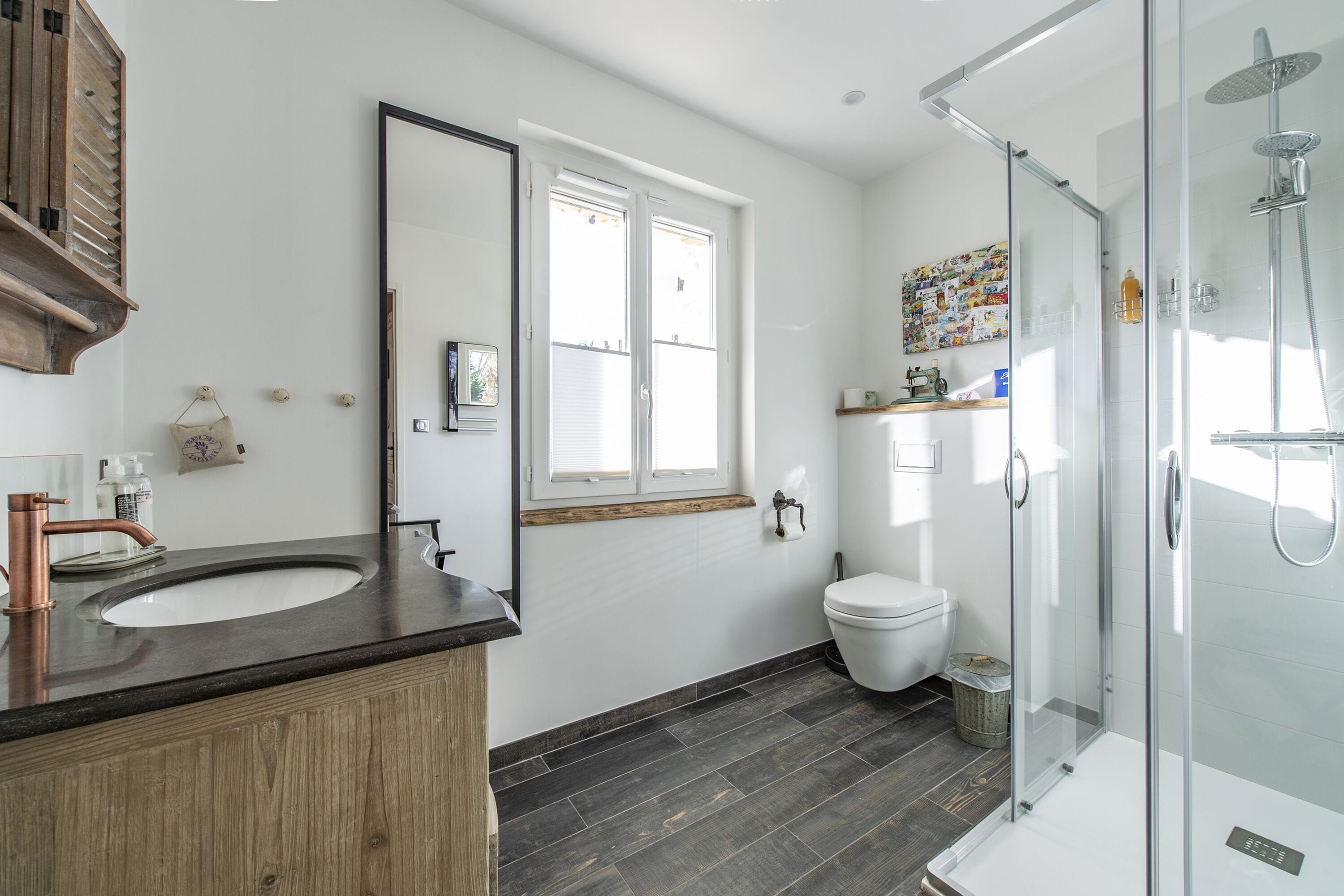 Une salle de bain moderne avec un meuble-lavabo en bois, un grand miroir, des toilettes et une douche à parois de verre.