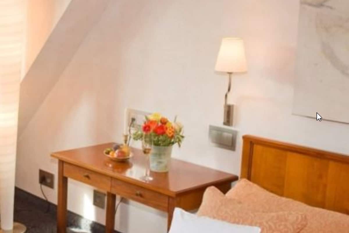 Habitació d'hotel amb un llit, una tauleta de nit amb una làmpada i una làmpada penjada a la paret.