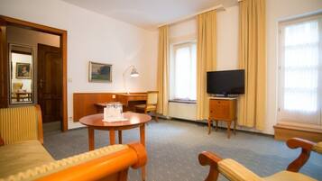 Une chambre d’hôtel équipée d’un lit, d’un bureau, d’une chaise, d’une télévision et d’une fenêtre avec des rideaux.