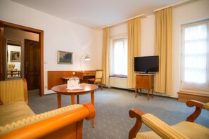 A hotel room with a bed, a desk, a chair, a television, and a window with curtains. - Zum Roten Bären (Freiburg im Breisgau)