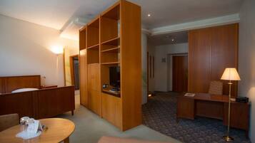 Une chambre d’hôtel comprenant un lit, un bureau, une chaise, une petite table, une armoire et une lampe.