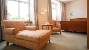 A cozy room with a sofa, armchair, and a small table. - Zum Roten Bären (Freiburg im Breisgau)