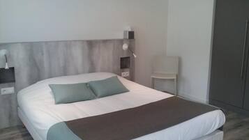 Un dormitorio moderno con una cama grande, una mesita de noche, una silla y un armario.