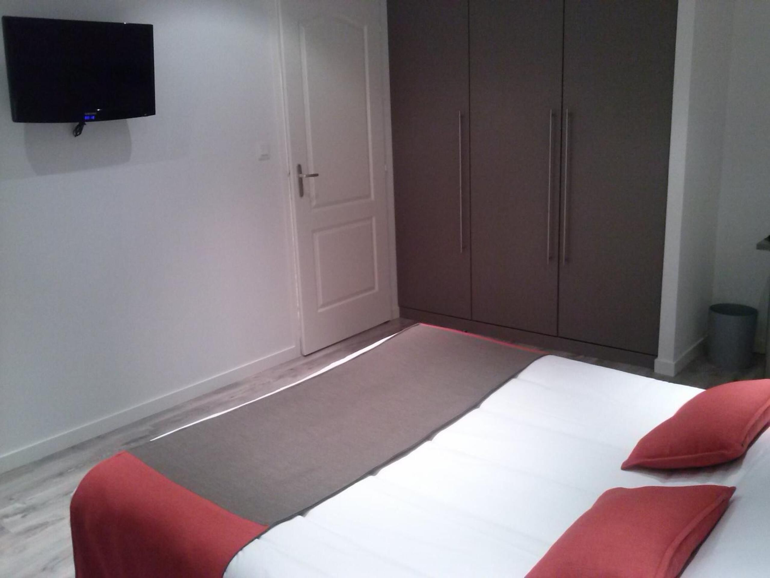 Un dormitorio con cama, armario y televisor en la pared.