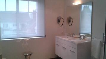 A bathroom with a window, a sink, a mirror, and a toilet.