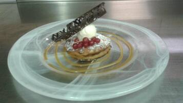 A dessert on a clear plastic plate with a caramel drizzle and a chocolate decoration.