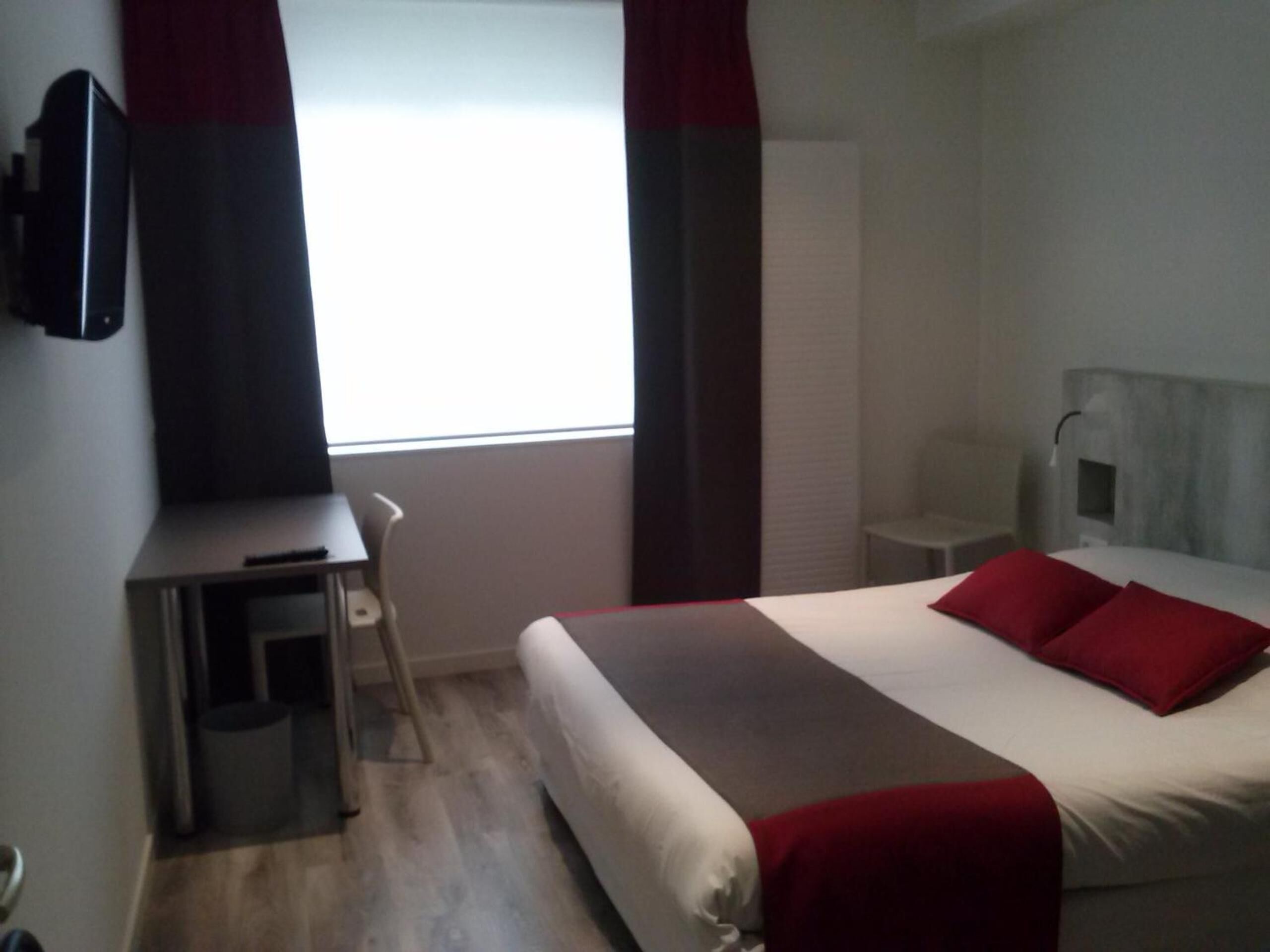 Une chambre d’hôtel avec un lit, un bureau et une chaise.