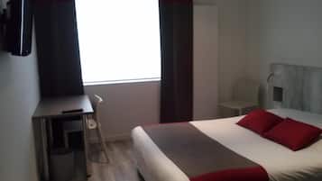 Une chambre d’hôtel avec un lit, un bureau et une chaise.