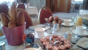 Une table mise pour le petit-déjeuner, avec du pain, des croissants et de la confiture.