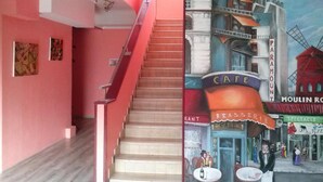 Un escalier menant à un espace café agrémenté d’une fresque représentant un paysage urbain.