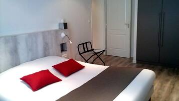 Une chambre à coucher avec un lit, deux oreillers rouges, une lampe de chevet, une chaise et une armoire.
