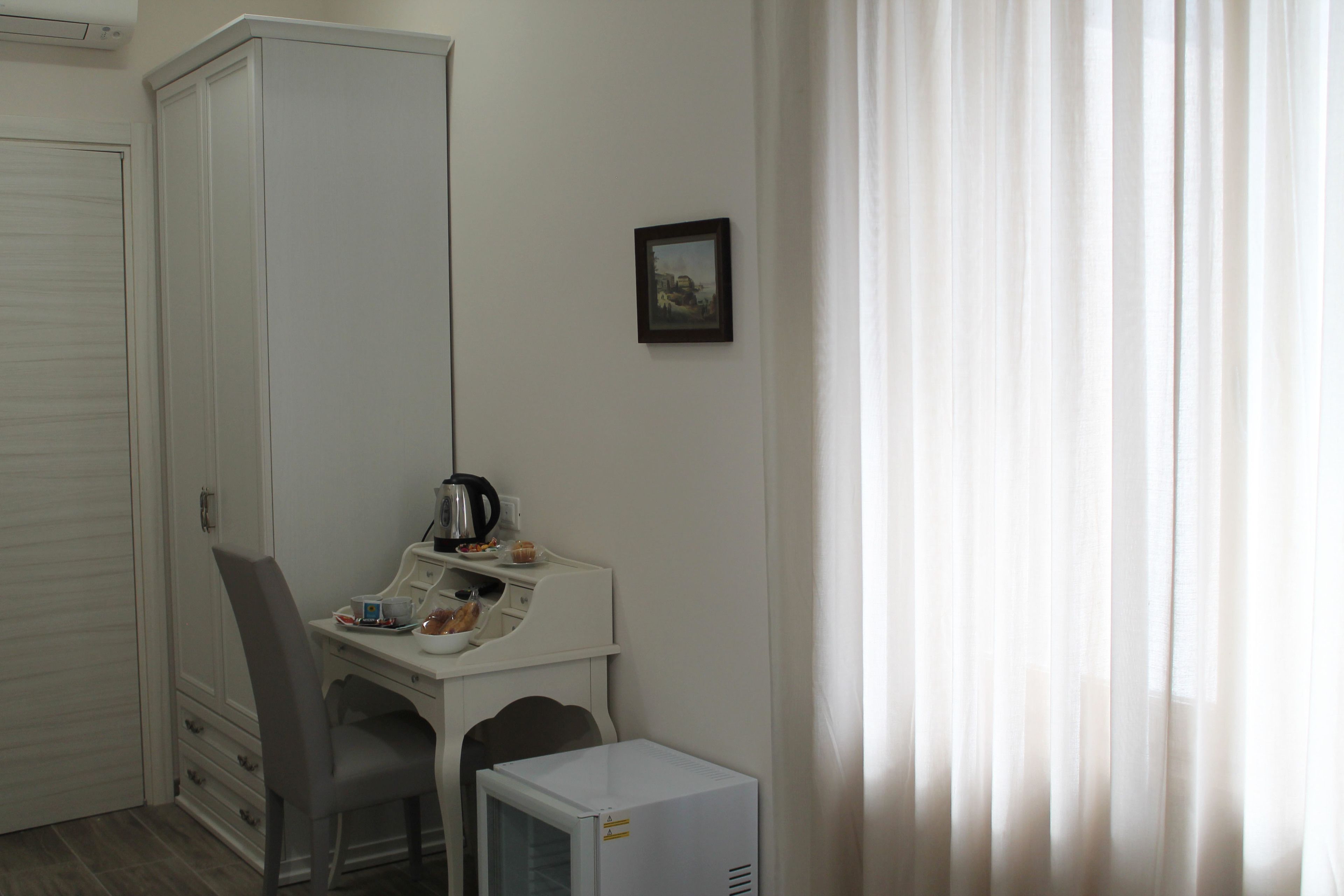 A small, neatly organized room with a desk, chair, and a compact refrigerator.
