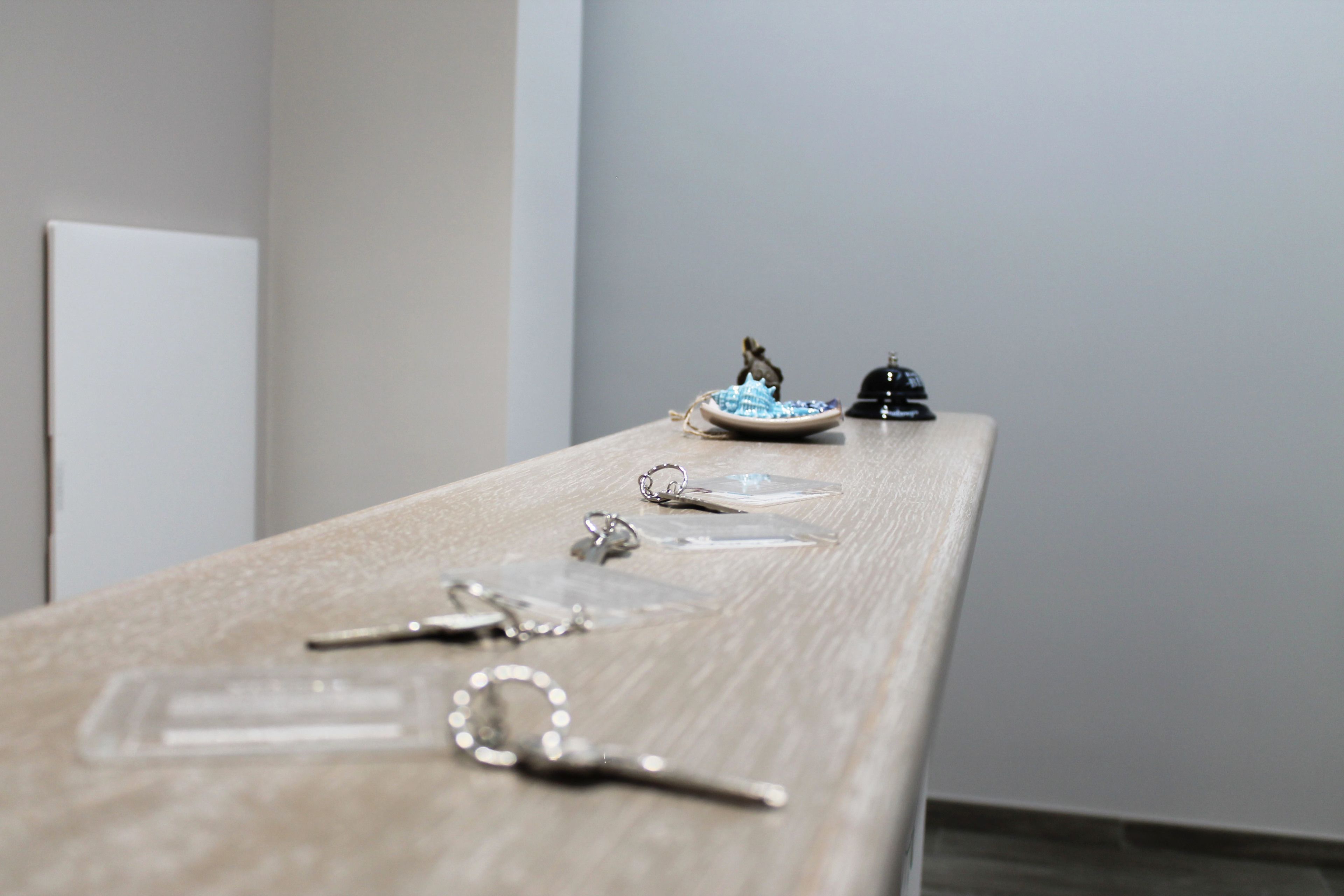 Una mesa de madera con llaves, una figurita pequeña y un objeto negro.