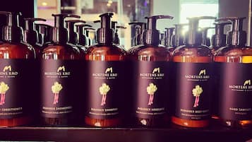 Presentación de productos Mortens Kro, incluyendo acondicionador, gel de ducha, champú, jabón de manos y loción corporal.