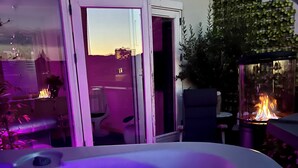 A hot tub with a view of a cityscape at dusk, a sliding glass door, and a fire feature. - Mortens Kro Boutique Hotel (Aalborg)