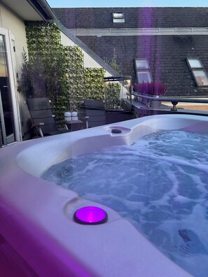 A hot tub with a purple light, surrounded by a garden with various plants and a view of the sky. - Mortens Kro Boutique Hotel (Aalborg)