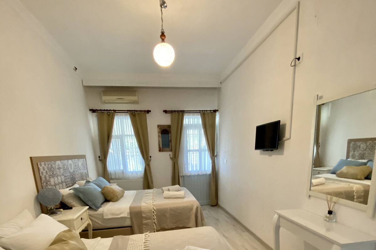 Una habitación de hotel con dos camas, un escritorio, un espejo y una televisión.