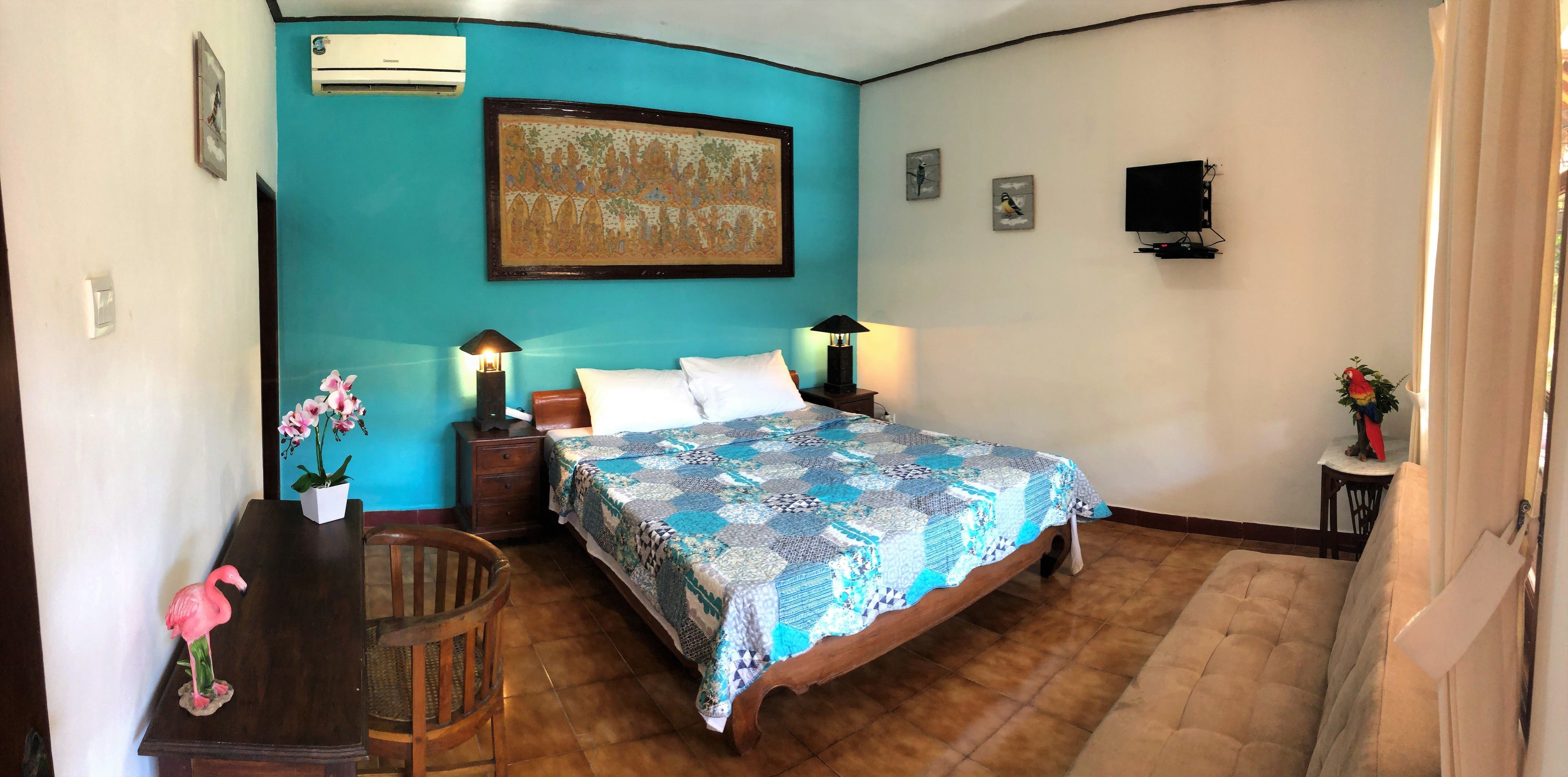 A bedroom with a bed, two bedside lamps, a nightstand, a wooden chair, a desk with a pink flamingo, and a potted plant.