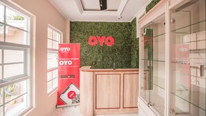 Un hall d’hôtel avec un ventilateur de plafond, un comptoir de réception et un mur sur lequel est inscrit le nom de l’hôtel : « OYO ».