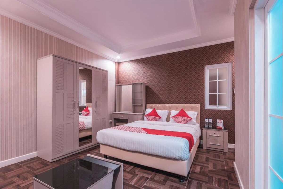 Ein Schlafzimmer mit Bett, Schrank, Nachttisch und Spiegel.