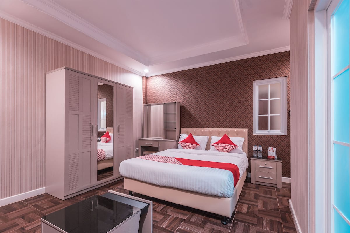 Ein Schlafzimmer mit Bett, Schrank, Nachttischen und einem Spiegel.