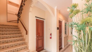 Un escalier recouvert de carreaux décoratifs, une porte en bois et un extincteur.