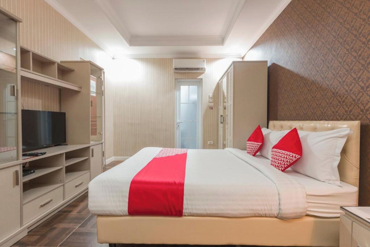 Une chambre d’hôtel équipée d’un lit, d’une télévision, d’une armoire et d’une porte donnant accès à une salle de bain.