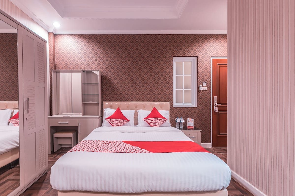 Ein Hotelzimmer mit Bett, Schrank, Nachttisch und Spiegel.