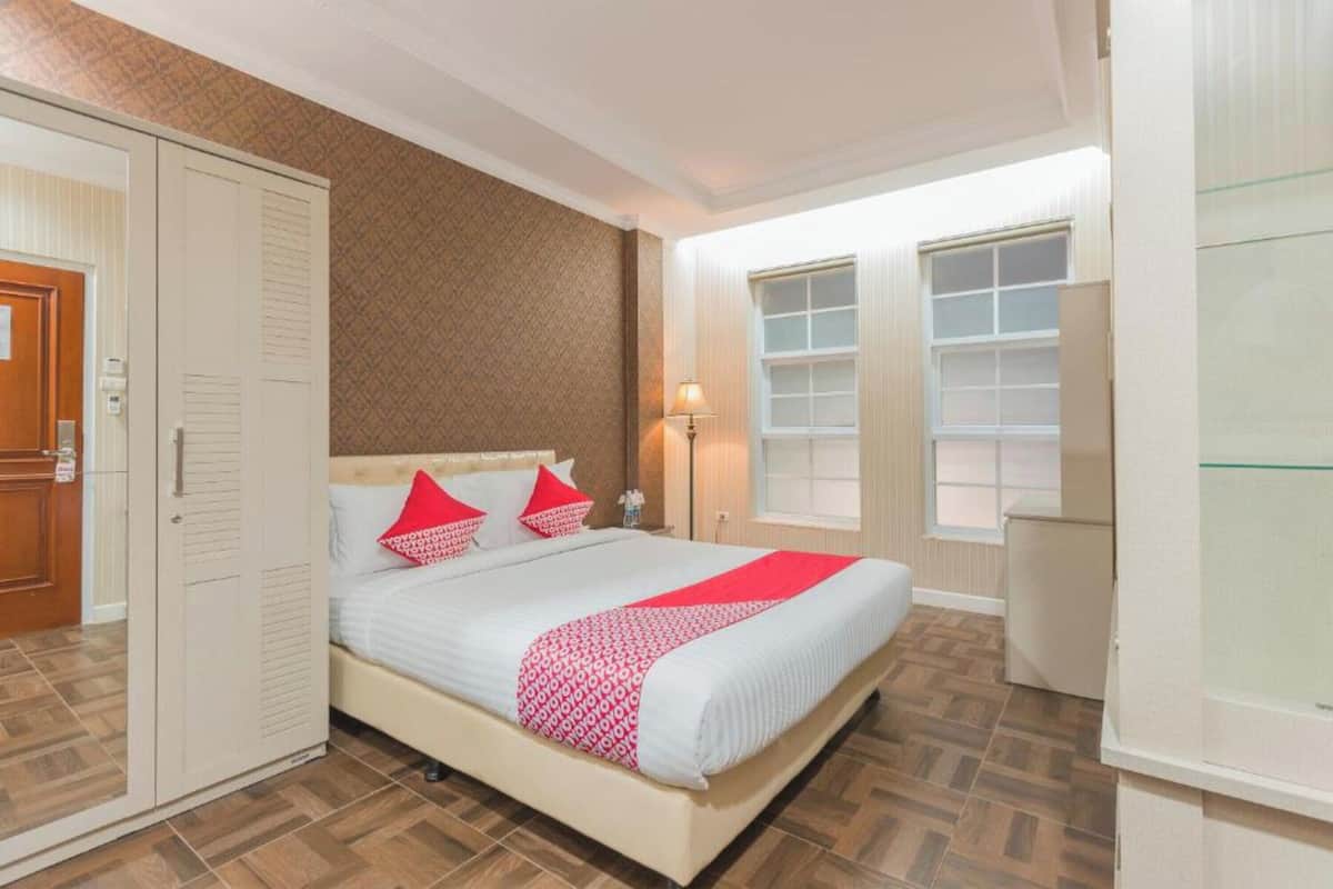 Ein Schlafzimmer mit Bett, Kleiderschrank, Nachttischlampe und einem Fenster.