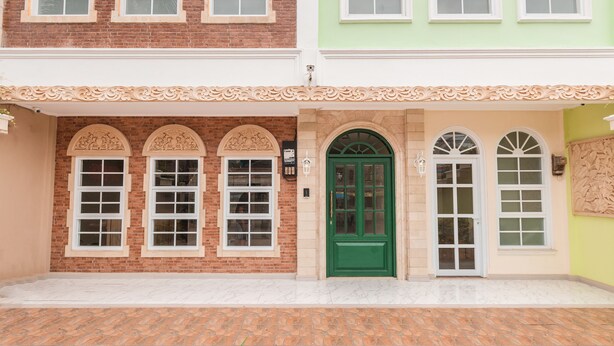 Un bâtiment à deux étages avec une façade en briques, une porte verte et des fenêtres à cadre blanc.