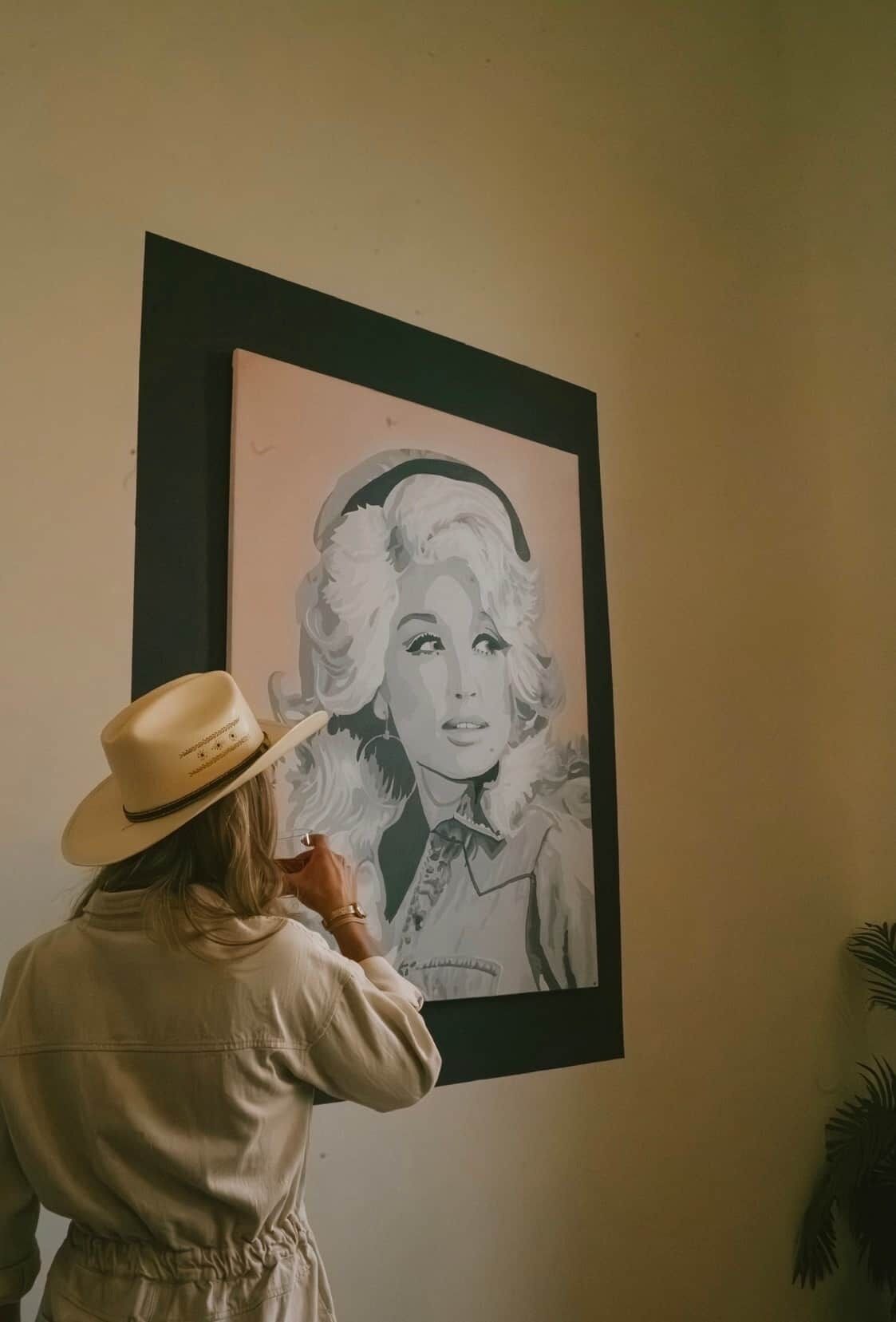 A person viewing a framed black and white portrait on a wall.