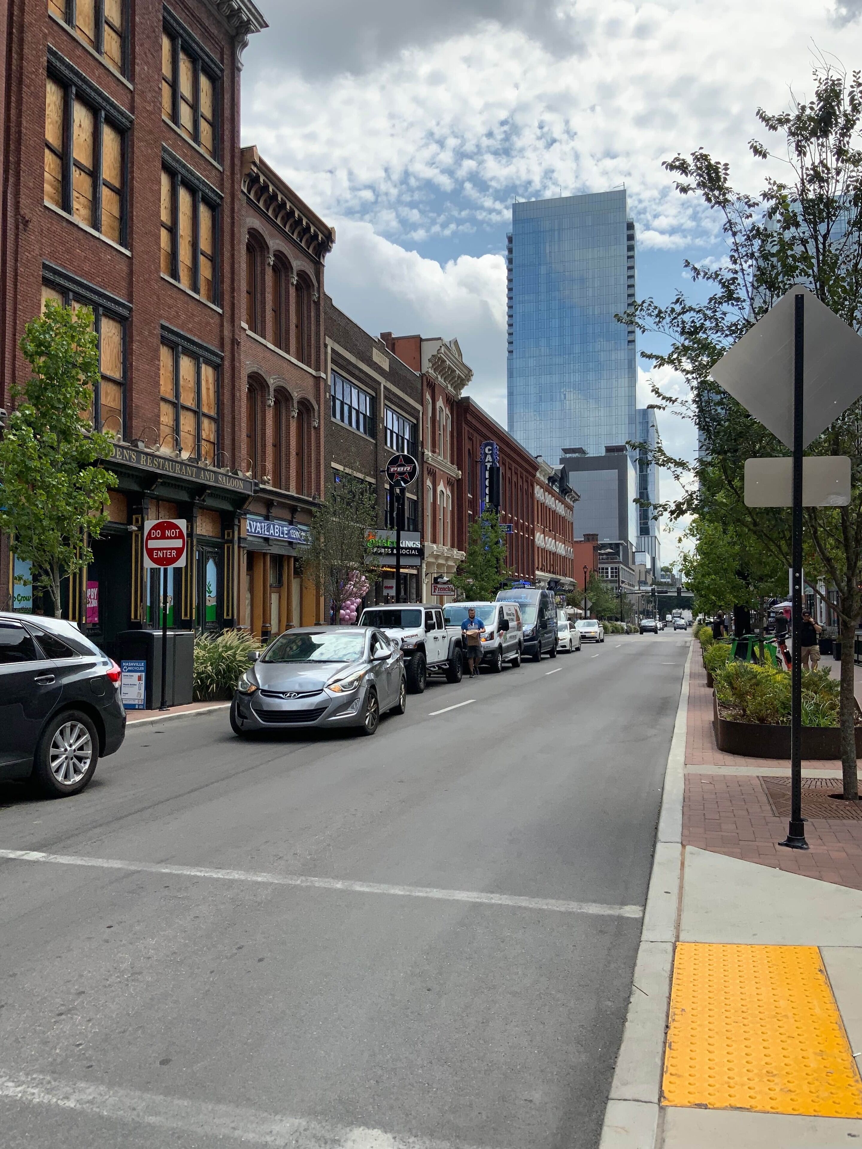 A street with buildings, cars, and a pedestrian crossing.