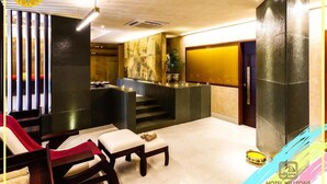Un vestíbulo de hotel con mostrador de recepción, zona de estar y escalera.