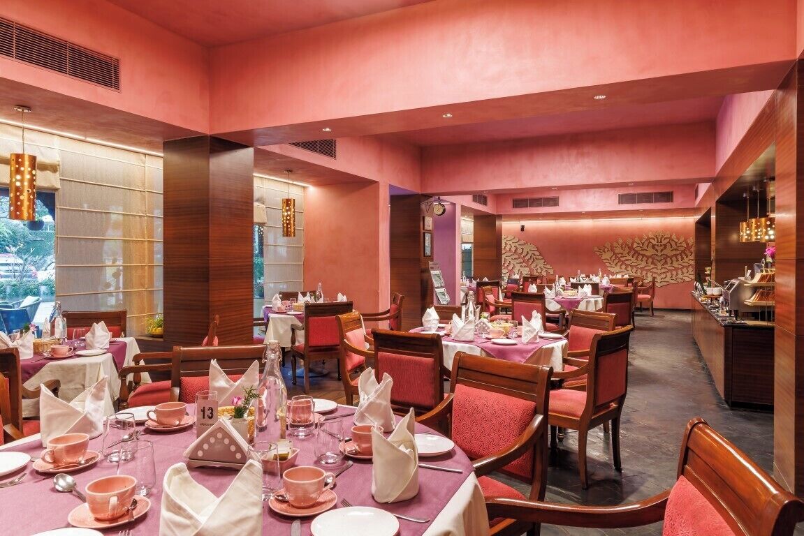 A restaurant with pink walls, wooden furniture, and tables set for dining.