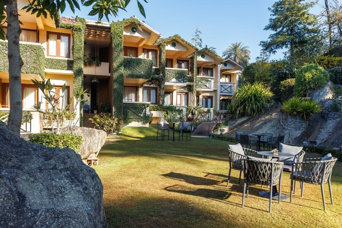 Un hotel con varios balcones, mobiliario exterior y abundante vegetación.
